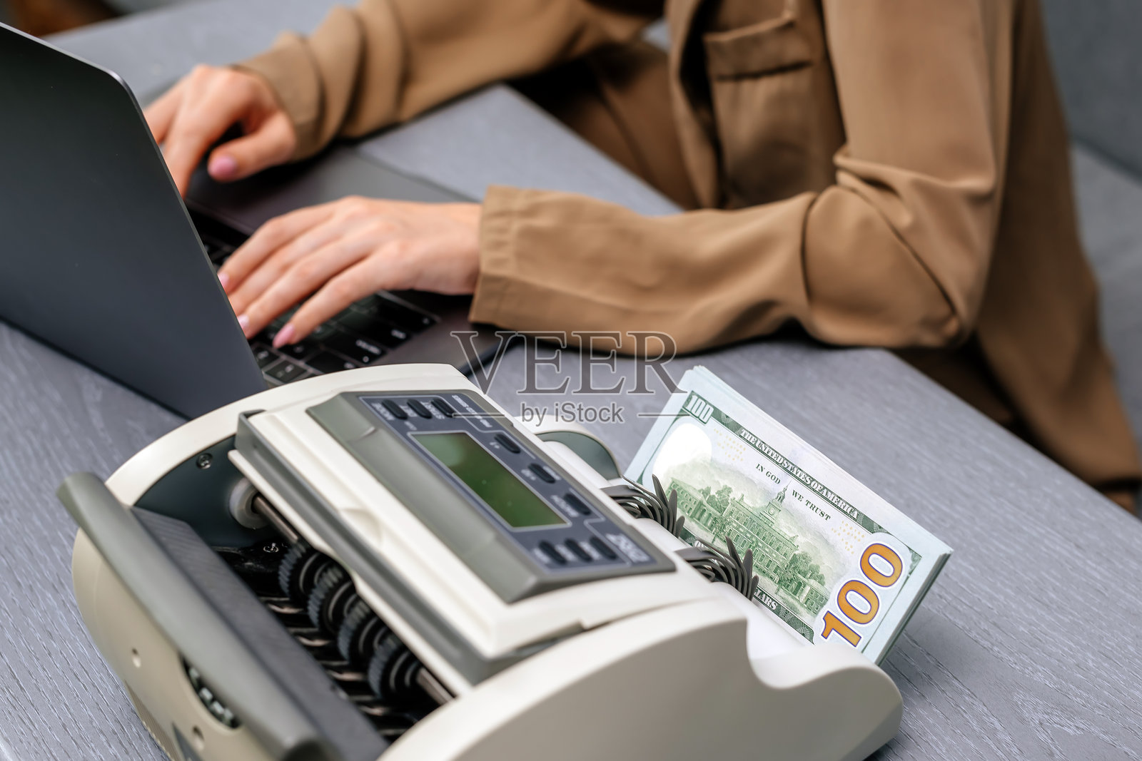 女商人在她的办公桌上使用金钱柜台，注重财务管理和商业运作的准确性。理想的金融，会计和成功的创业主题。照片摄影图片