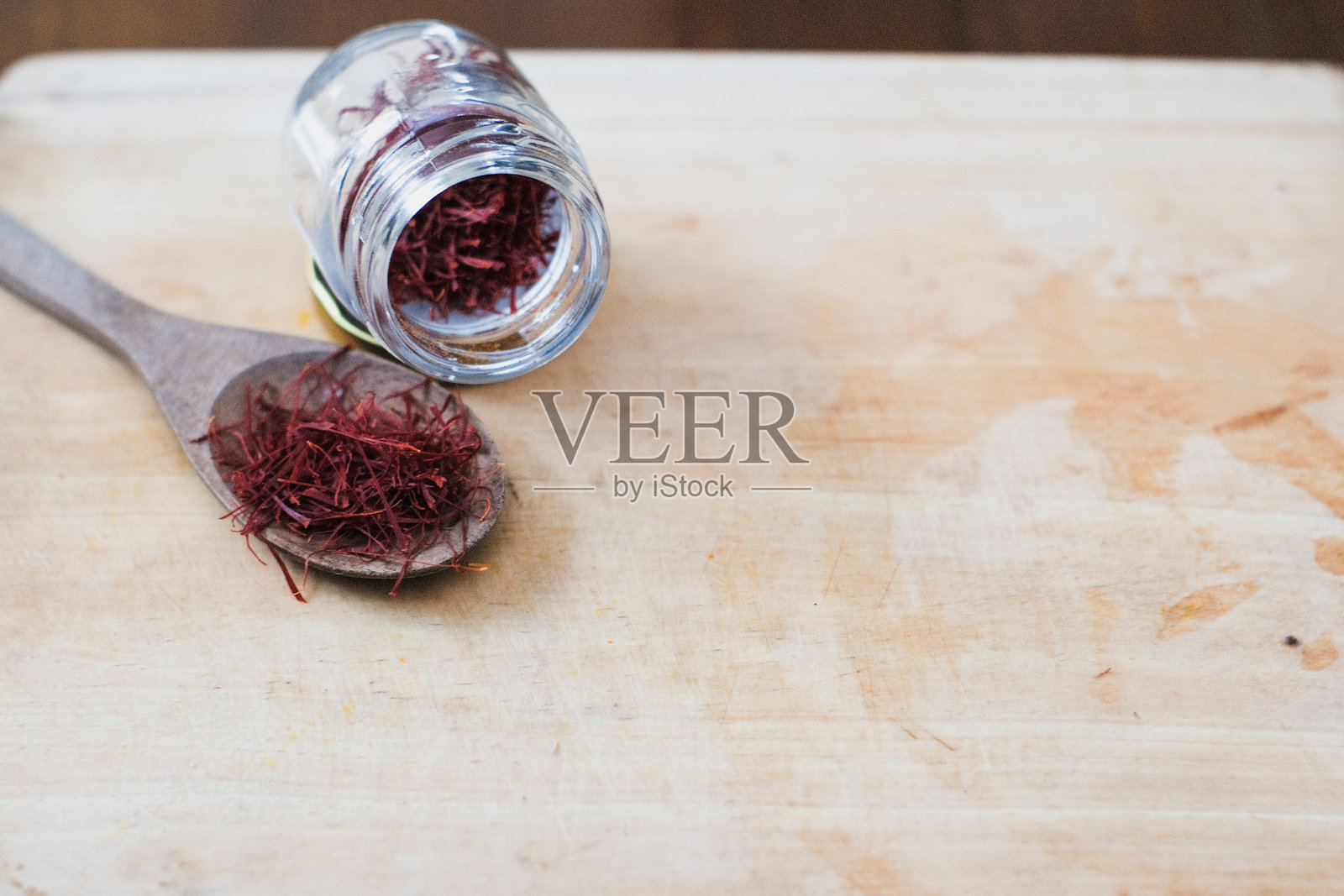 干藏红花线在一个玻璃瓶和木勺，在木制砧板照片摄影图片