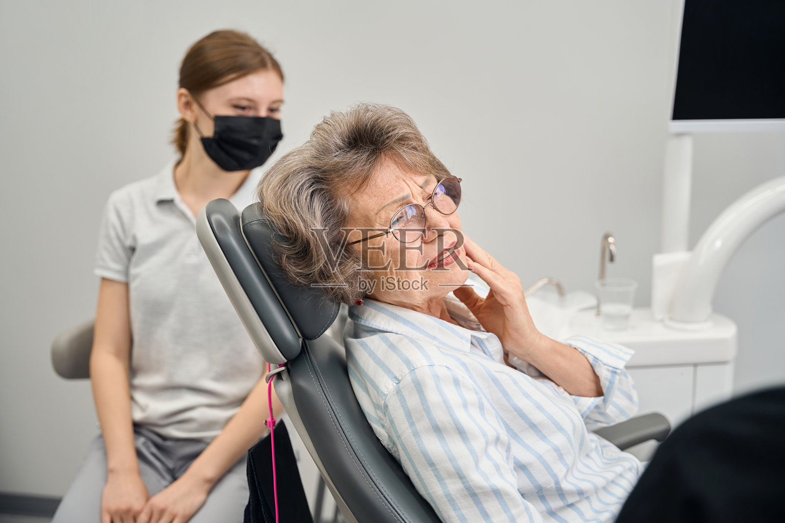 一位老妇人在牙医办公室向专家抱怨牙痛照片摄影图片