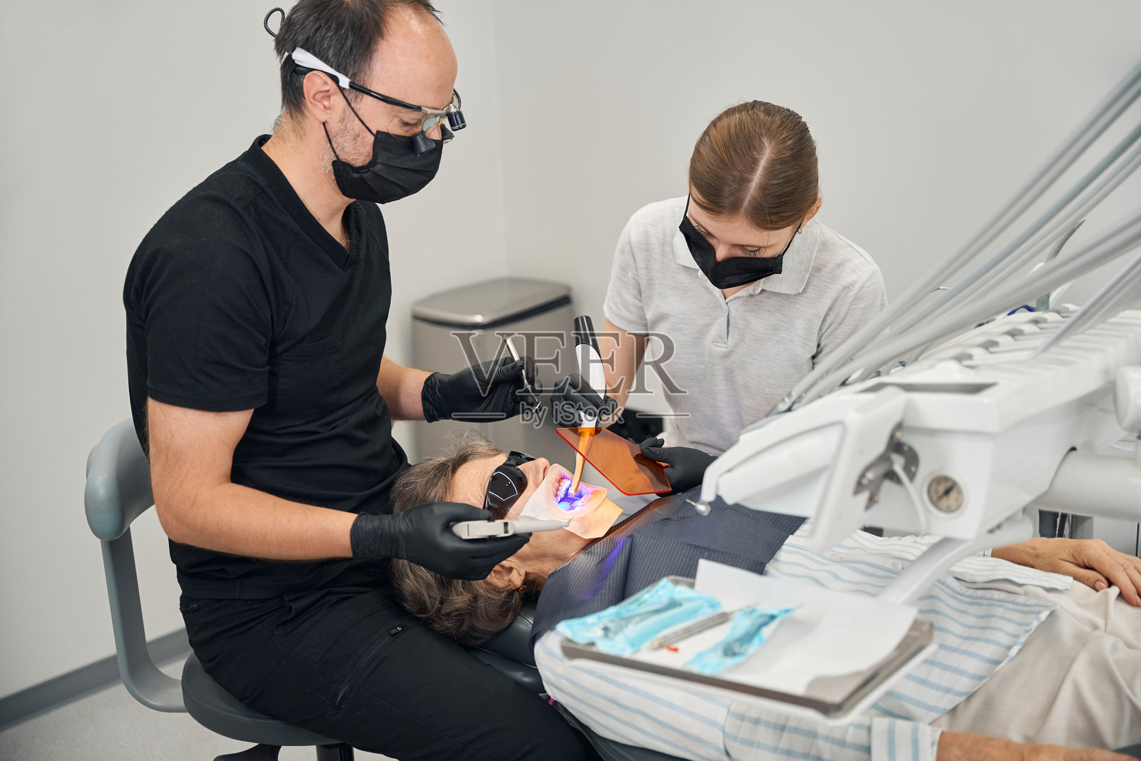 医生和助手给病人做了光聚合物填充物照片摄影图片