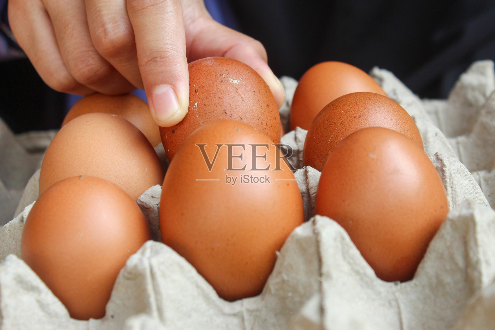 女人的手拿着鸡蛋盒里的鸡蛋。一个鸡蛋被带去煮熟照片摄影图片