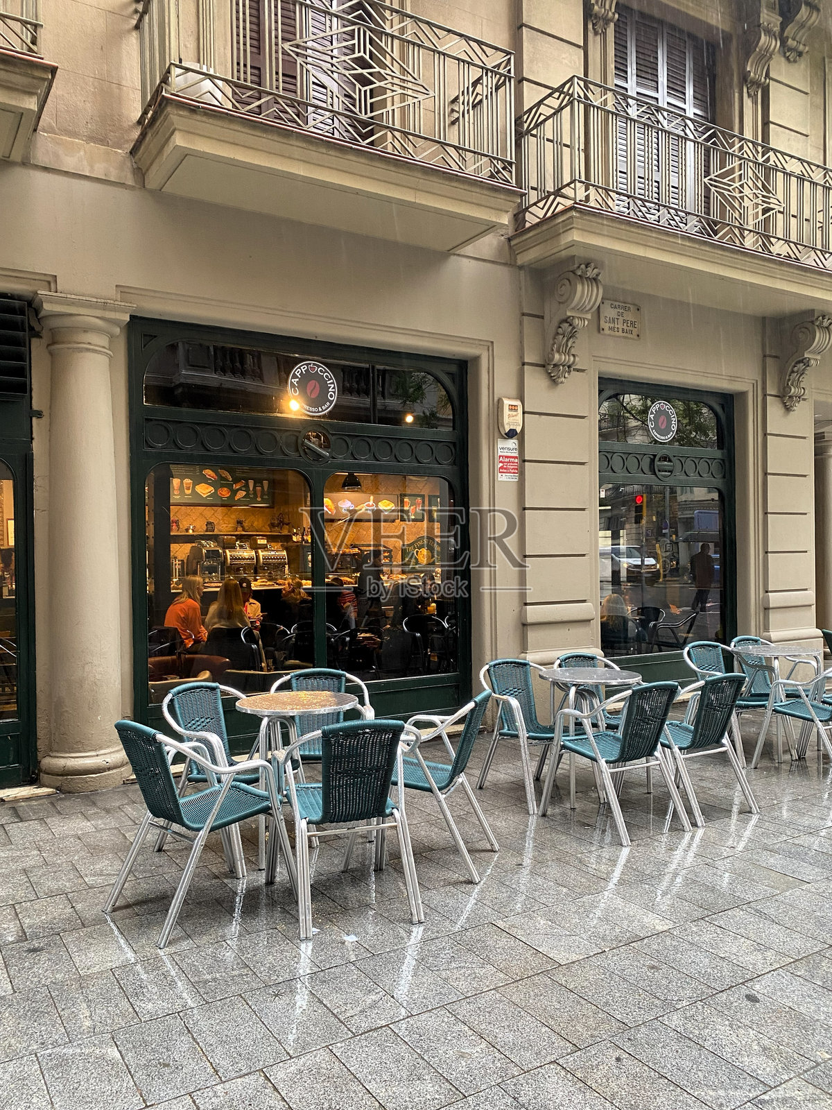 巴塞罗那，顾客坐在人行道上的咖啡馆里避雨照片摄影图片