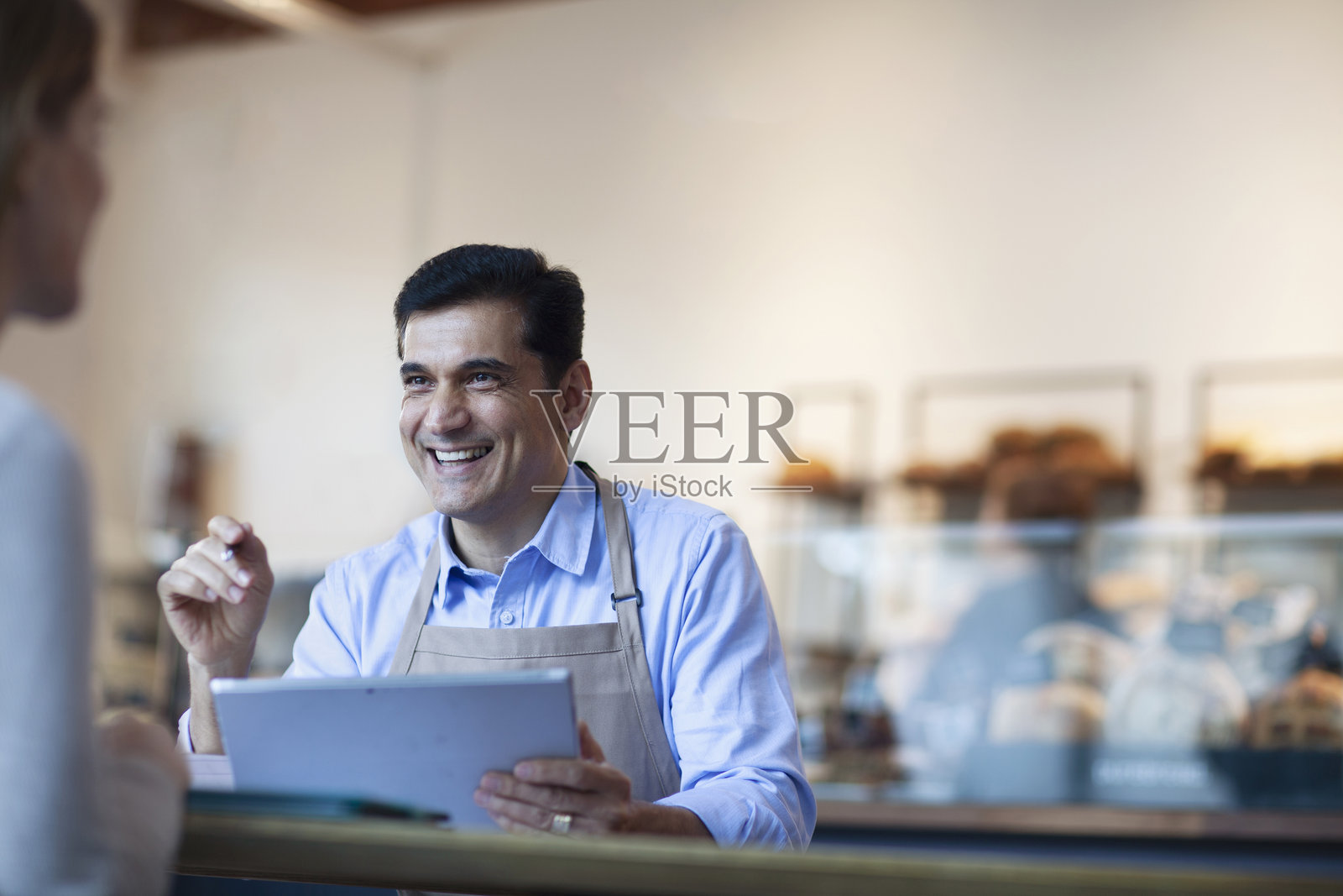 中东成熟男人在面包店咖啡馆使用平板电脑规划小企业，与女财务顾问交谈照片摄影图片