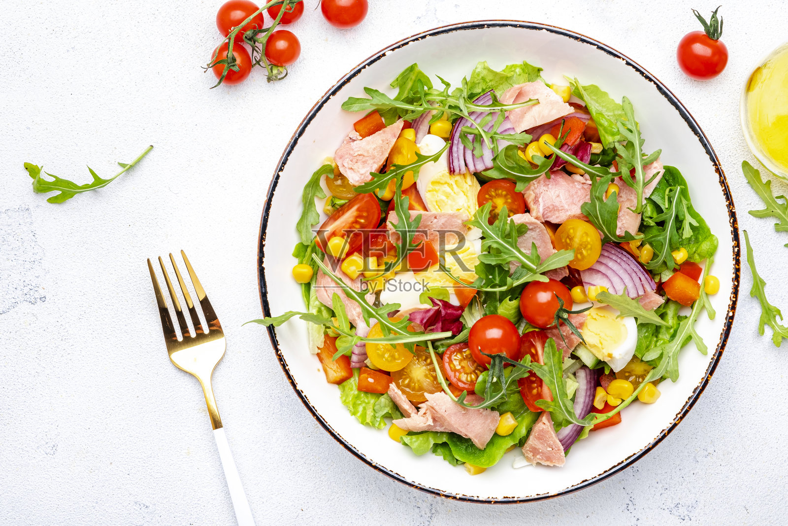 美味的金枪鱼蔬菜沙拉，配以西红柿、洋葱、玉米、鸡蛋、辣椒粉、生菜和芝麻菜。白色背景，俯视图照片摄影图片