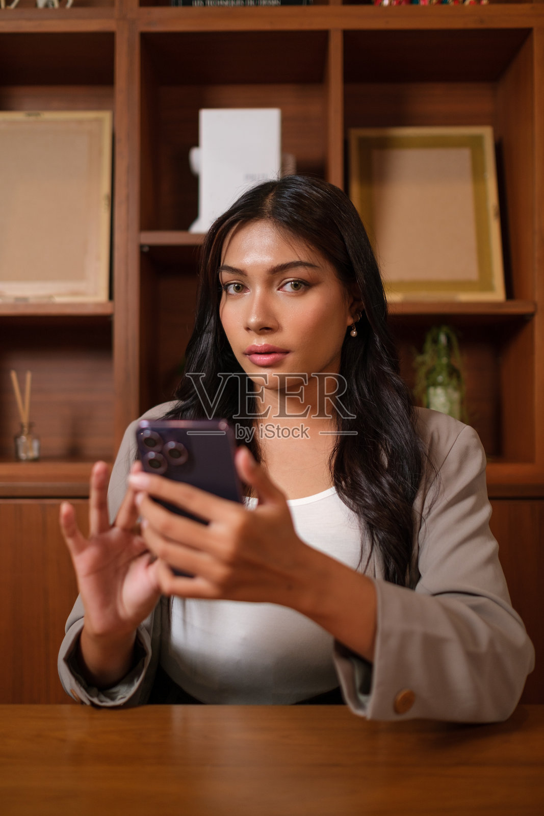 自信的女商人在办公室使用手机的肖像。照片摄影图片