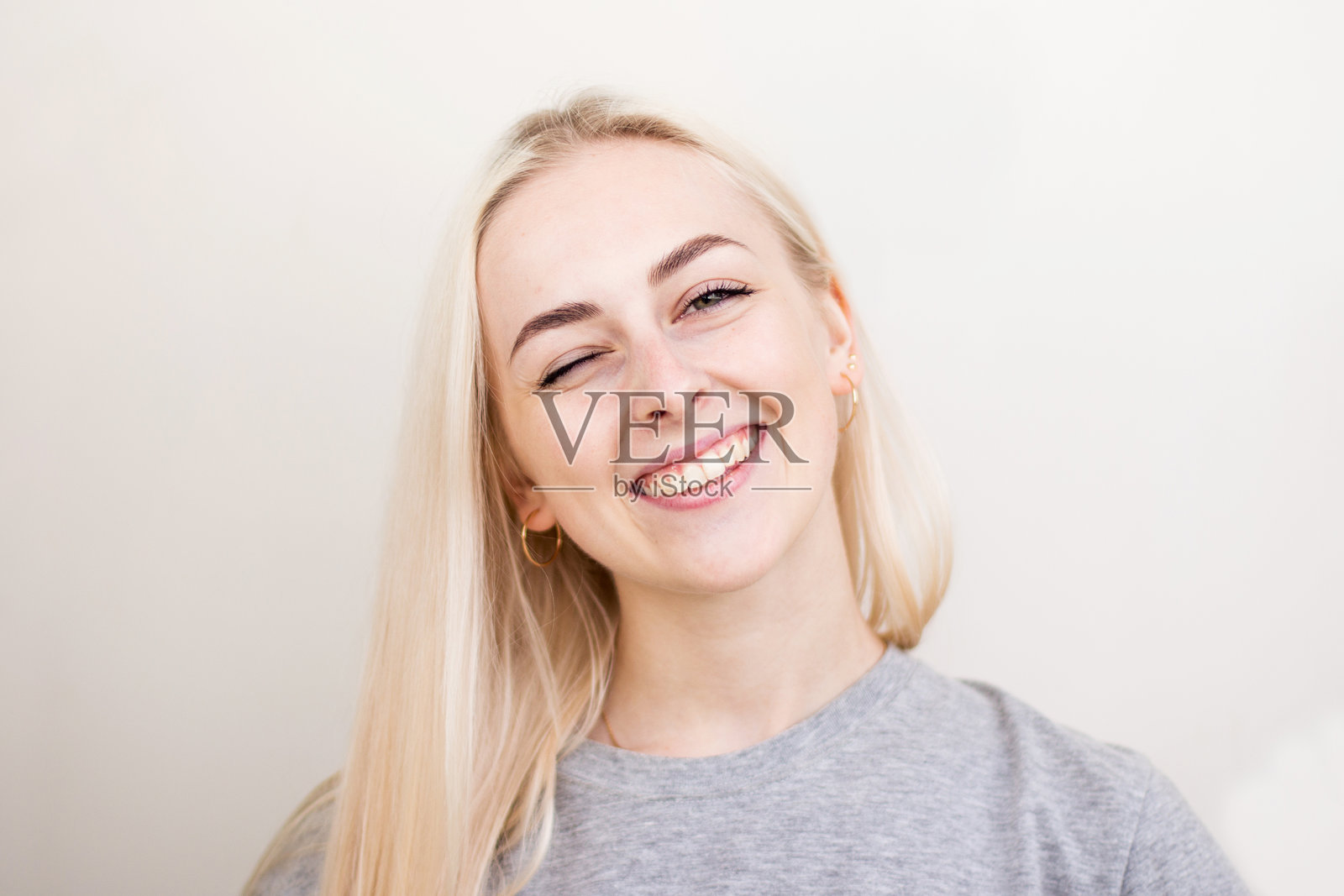 漂亮的微笑快乐的女性，金发，穿着随意，看着镜头满意，是幸福的。工作室拍摄的漂亮女人照片摄影图片