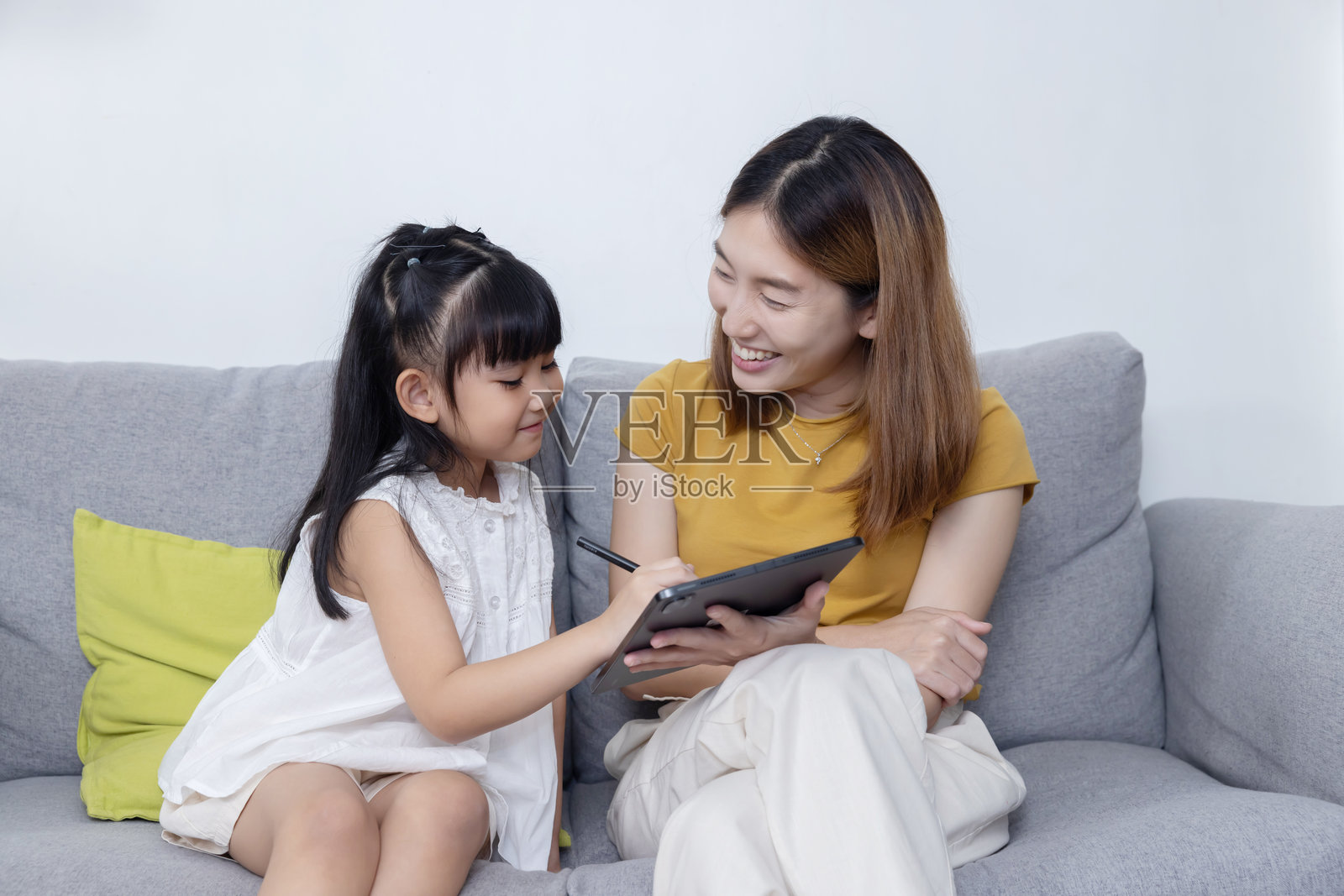 母亲看着女儿在写字板上画画照片摄影图片