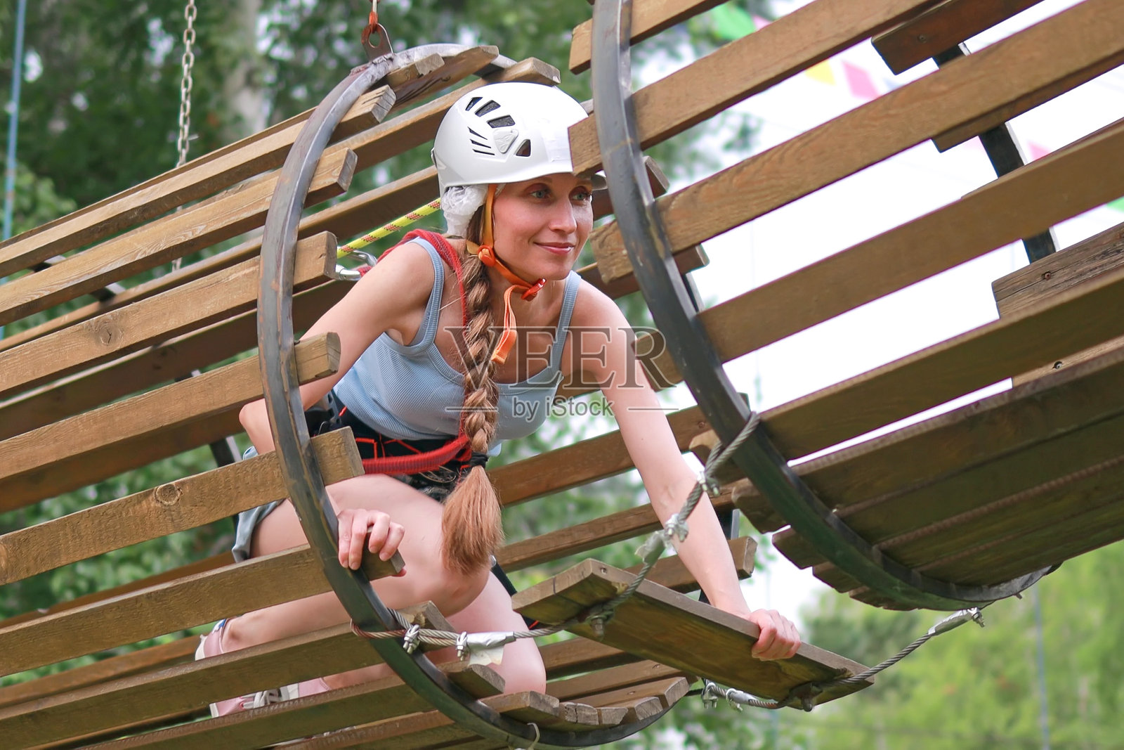 一名穿着装备的妇女在绳索公园的木管中通过障碍物照片摄影图片