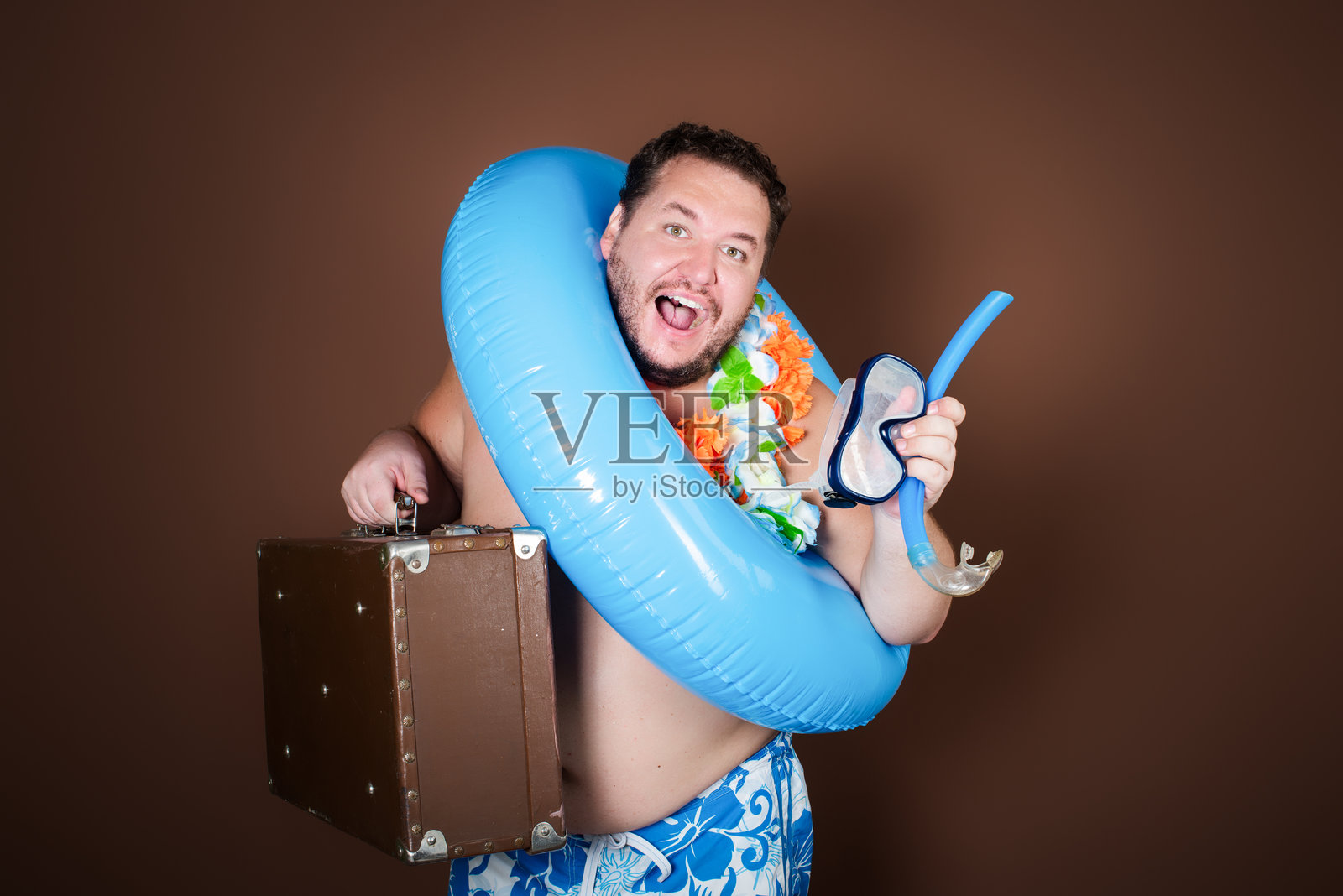 带着充气戒指的滑稽胖子要去度假了。照片摄影图片