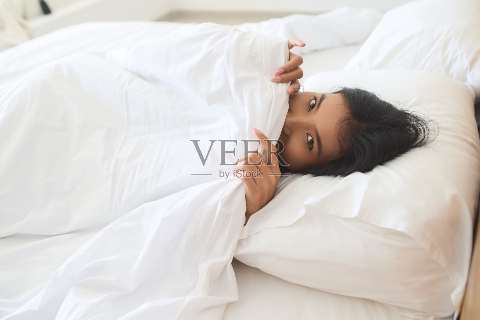 年轻女子舒适地躺在舒适的白色床单上照片摄影图片
