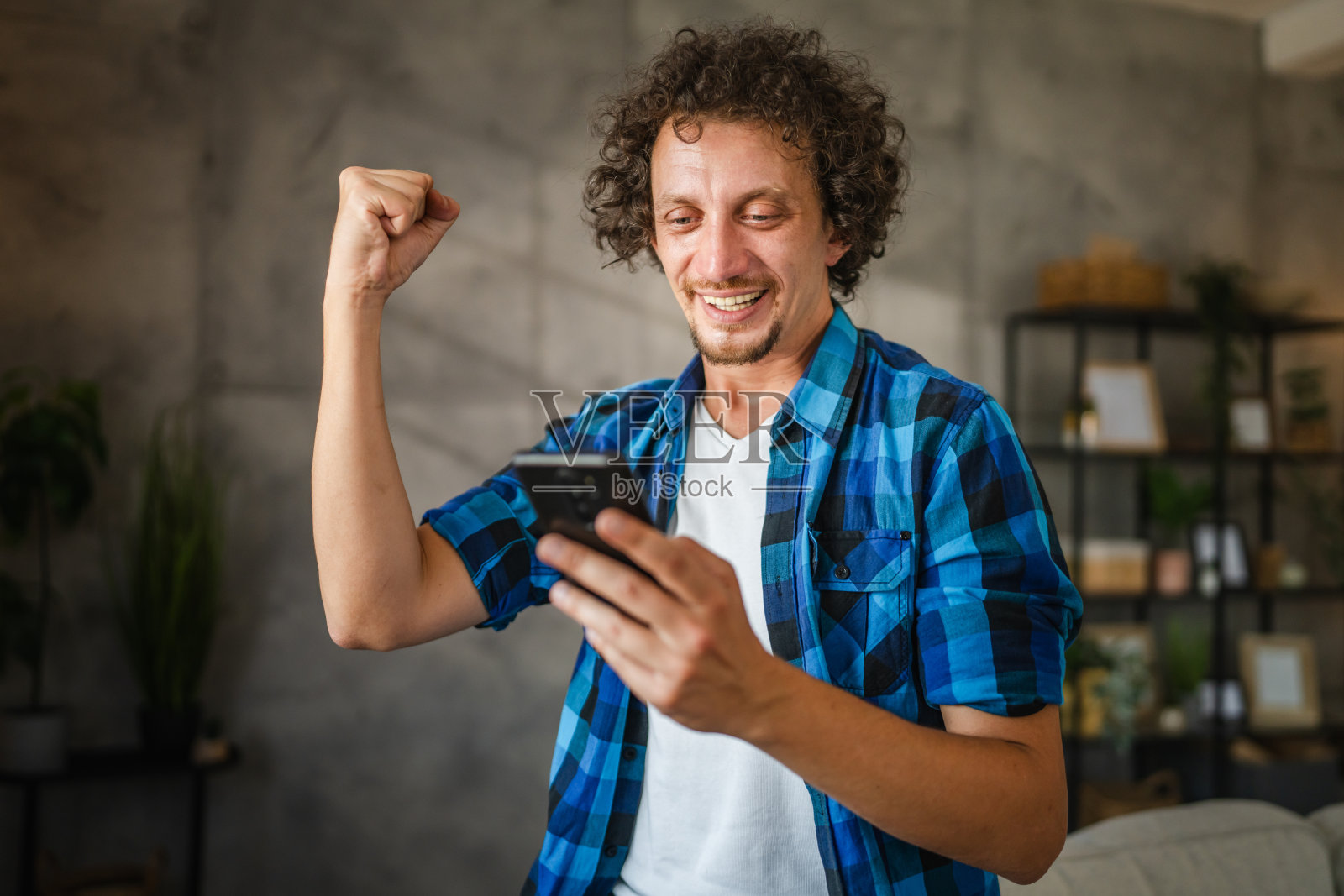兴奋的成年白种人用手机做胜利者的手势照片摄影图片