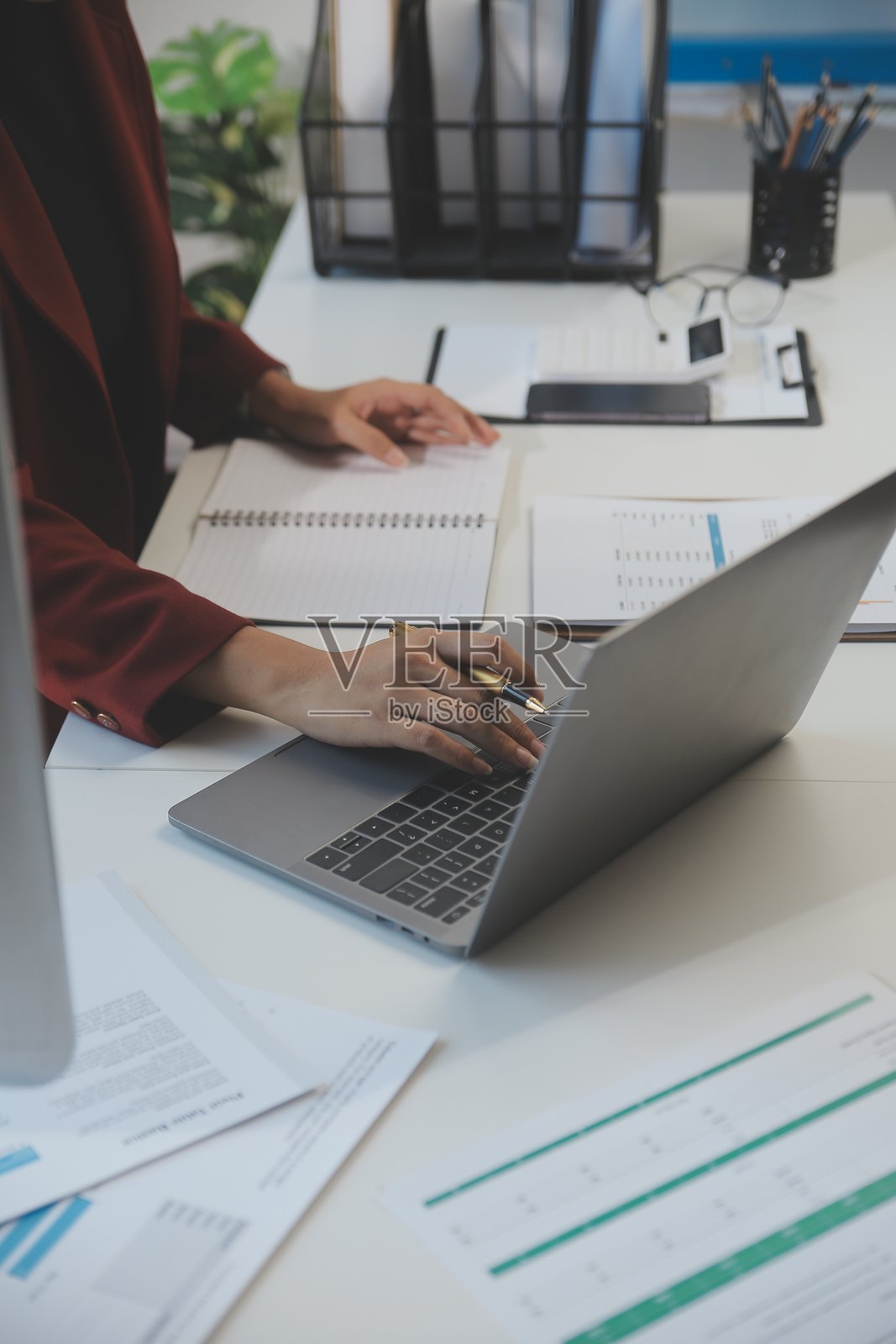 专业女商人通过笔记本电脑在办公室工作的剪裁图像，年轻的女经理坐在现代阁楼上使用便携式电脑设备，照明灯，工作流程概念照片摄影图片