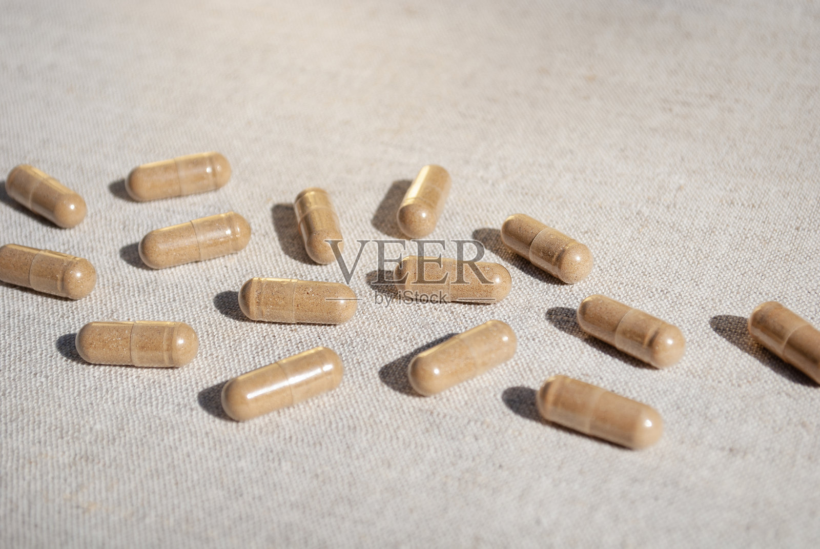 棕色的胶囊散落在米色桌布的桌子背景上照片摄影图片