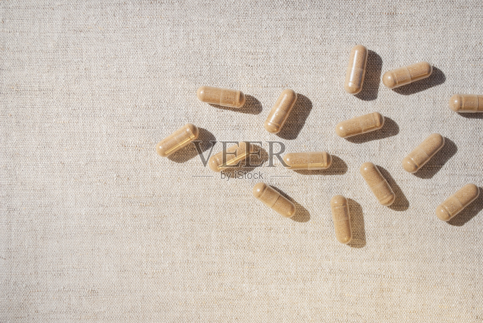 棕色的胶囊散落在米色桌布的桌子背景上照片摄影图片