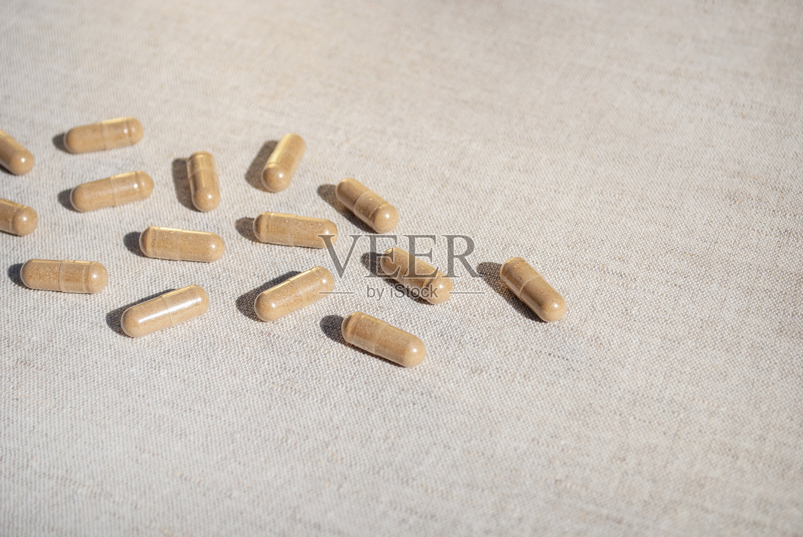 棕色的胶囊散落在米色桌布的桌子背景上照片摄影图片