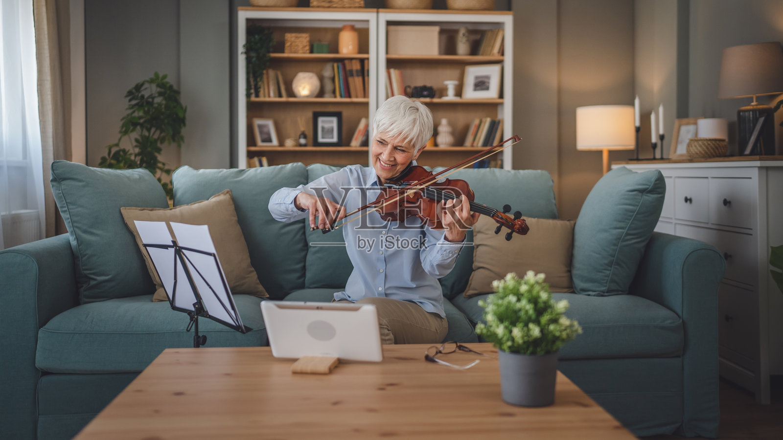 成熟的白种老年妇女在家学习拉小提琴练习照片摄影图片