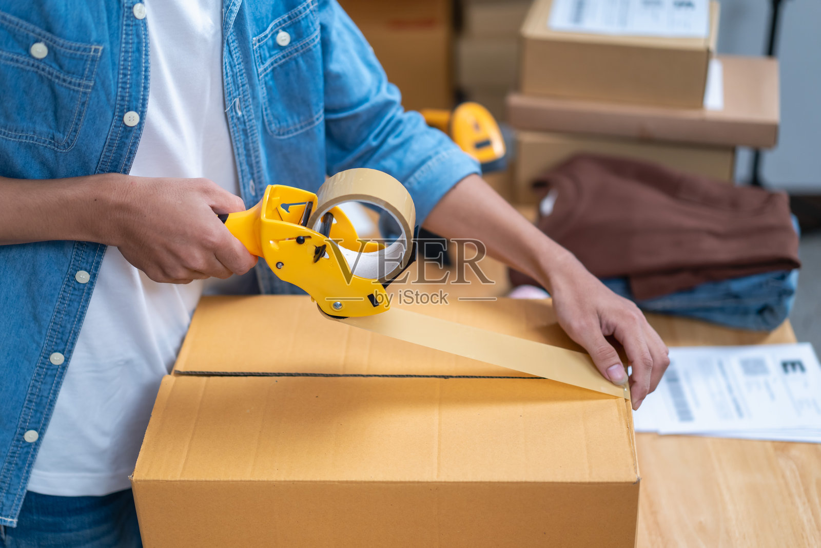 年轻的亚洲人，经销商，网店老板，小企业主，站在仓库里，准备运送货物，拿着包裹箱。照片摄影图片