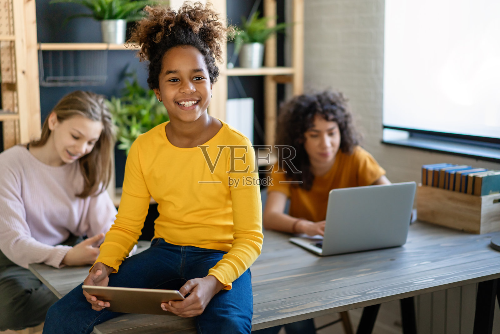 快乐的多民族青少年拿着电子设备一起学习。照片摄影图片