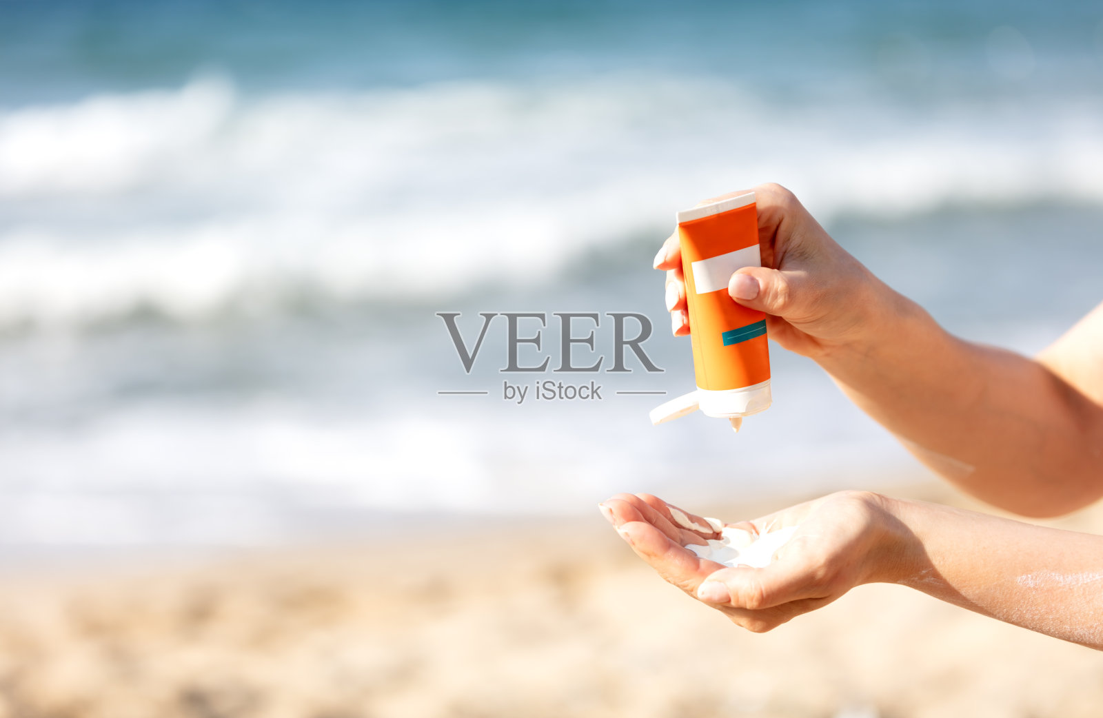 女士在沙滩上用手涂抹防晒霜照片摄影图片