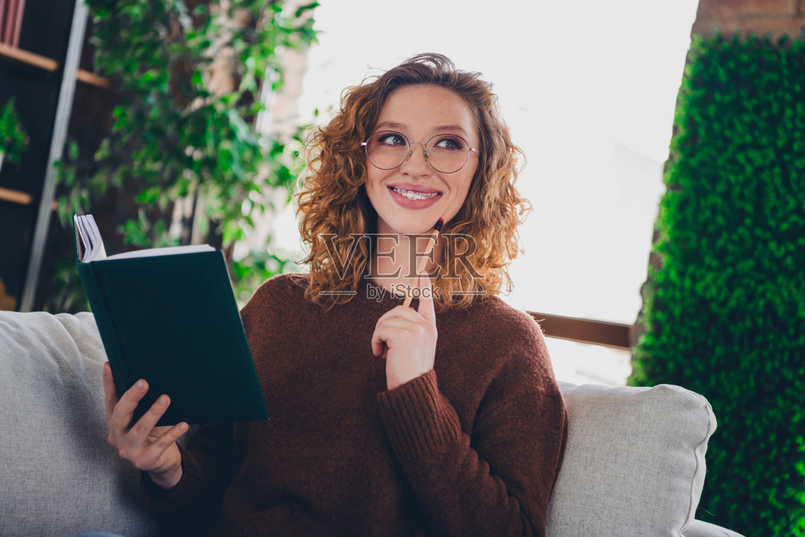 家庭可爱可爱的照片可爱的女人穿着时髦的衣服抱规划师认为室内房子的家照片摄影图片