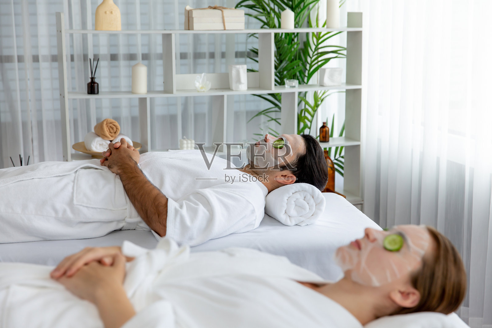 一对顾客沉迷于黄瓜面部护理。静照片摄影图片