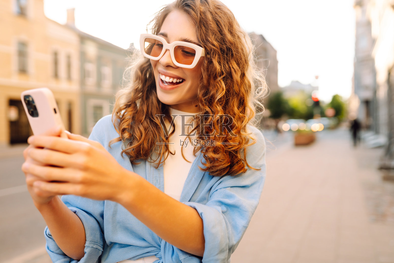 傍晚时分，一名女子在水边享受阳光明媚的一天，同时愉快地自拍。照片摄影图片