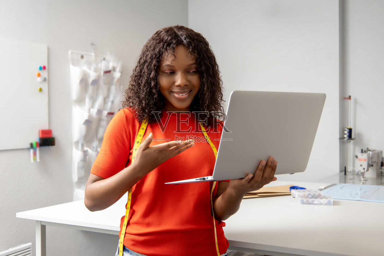 拿着笔记本电脑的非洲裔年轻女裁缝在电话里讨论着什么照片摄影图片