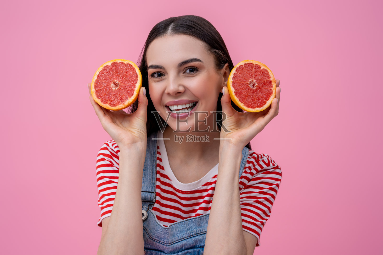 可爱的微笑的年轻女子手里拿着葡萄柚片照片摄影图片