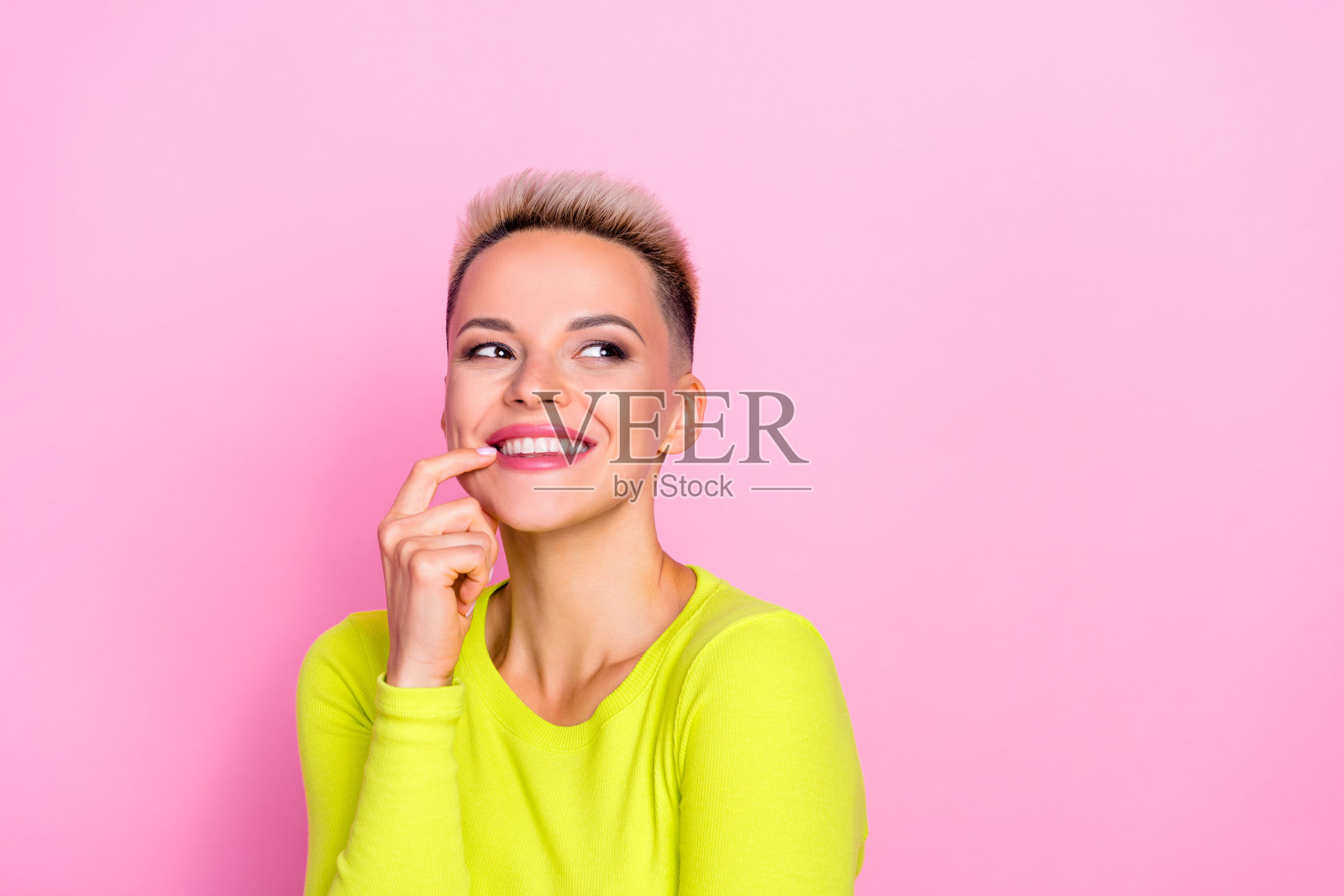 可爱的开朗的女士的肖像微笑手指触摸嘴唇看起来空白的空间孤立在粉红色的背景照片摄影图片