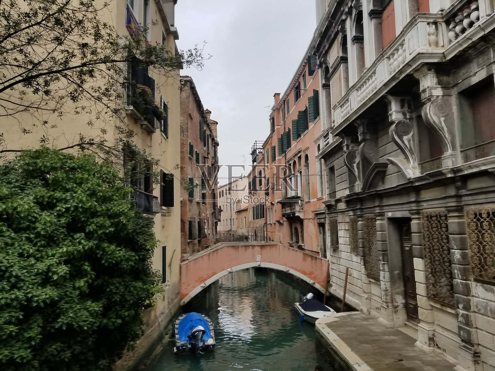 阴天，小船从桥下经过，威尼斯宁静的运河景色照片摄影图片