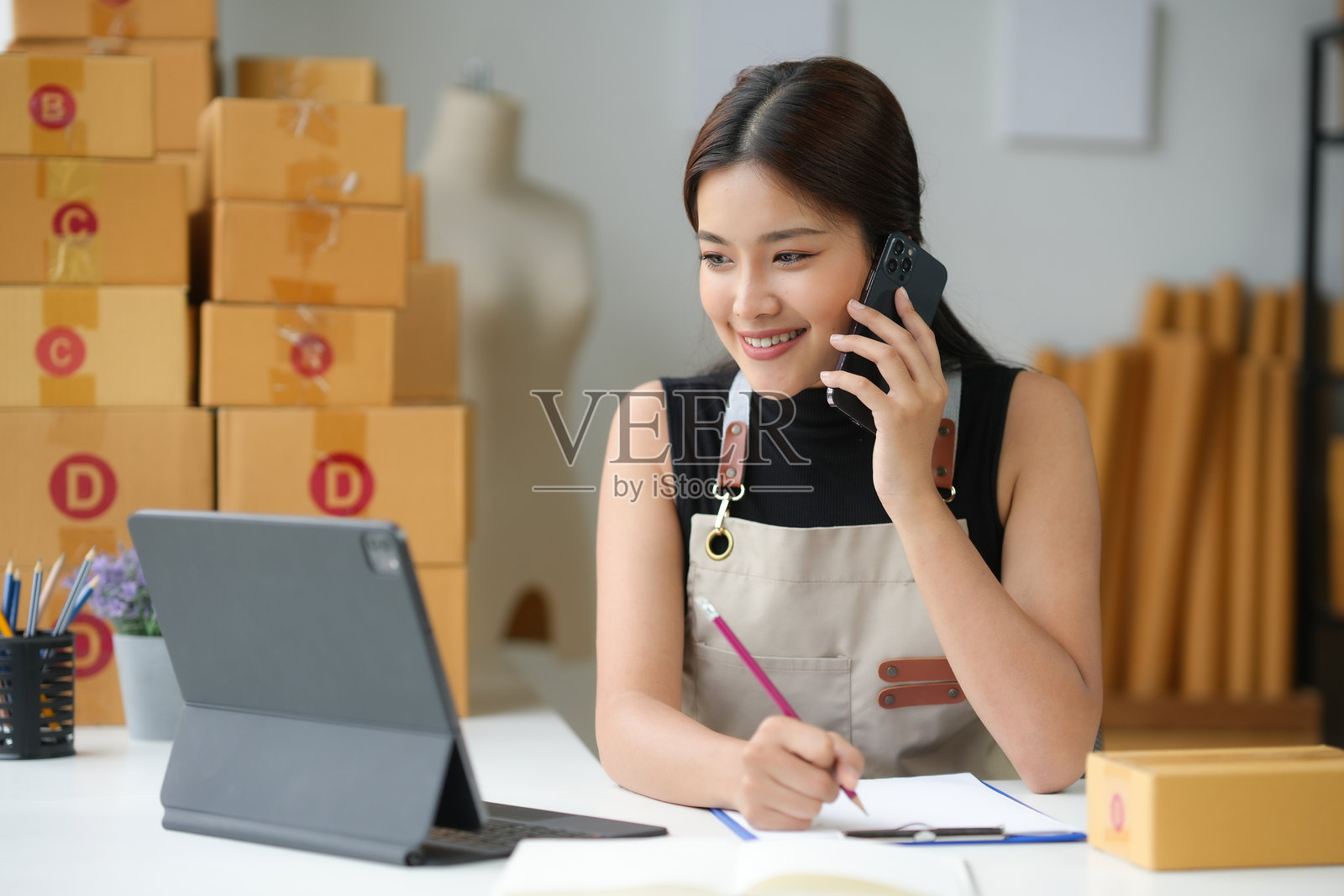 亚洲女企业家正在打电话并记下订单照片摄影图片