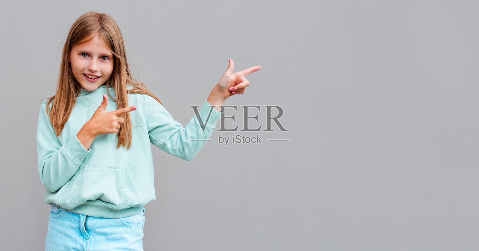 微笑的女人指着灰色背景上孤立的拷贝空间照片摄影图片