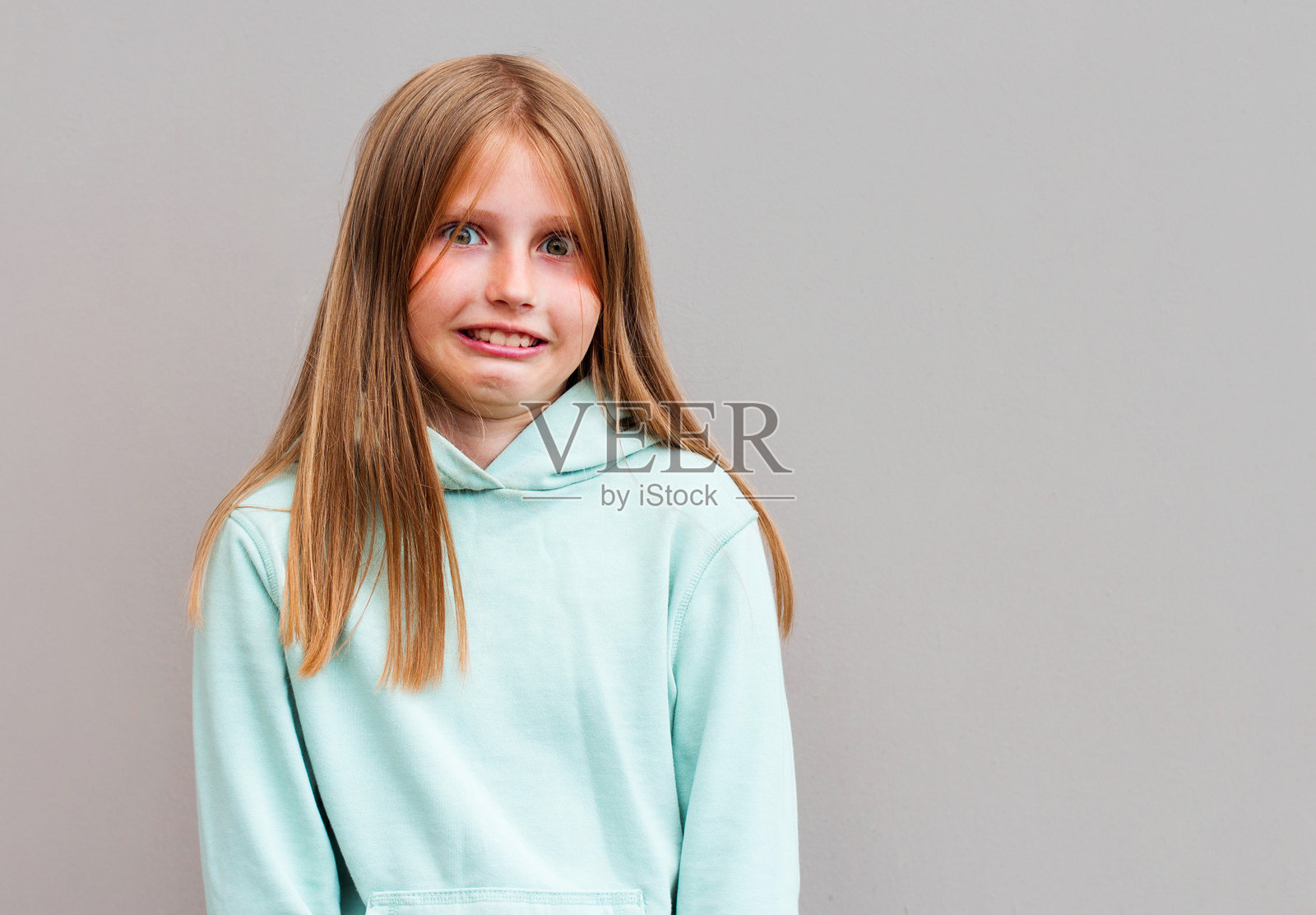 工作室拍摄的可爱的金发女孩，带着沉思和狡猾的表情，侧视，扬起眉毛，好像有什么好主意，计划什么照片摄影图片