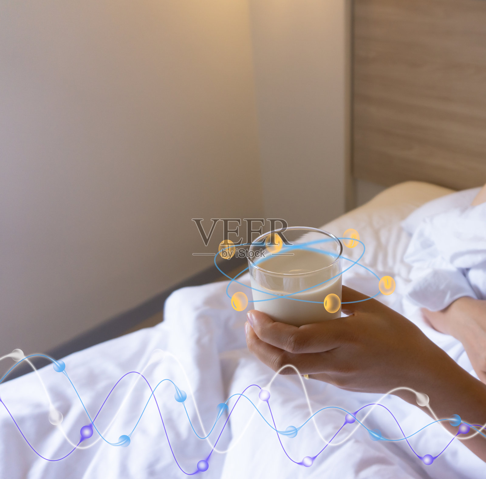 一位亚洲女性躺在床上，端着一杯豆浆，在床上喝牛奶，醒来时发现自己的卧室里有一张白色的床和毯子。照片摄影图片