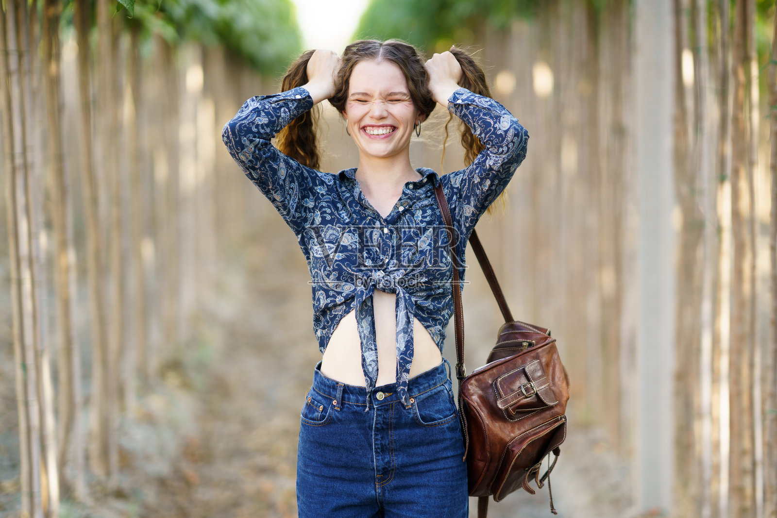 一个快乐的年轻女子，穿着五颜六色的花上衣，愉快地享受着大自然的美丽照片摄影图片
