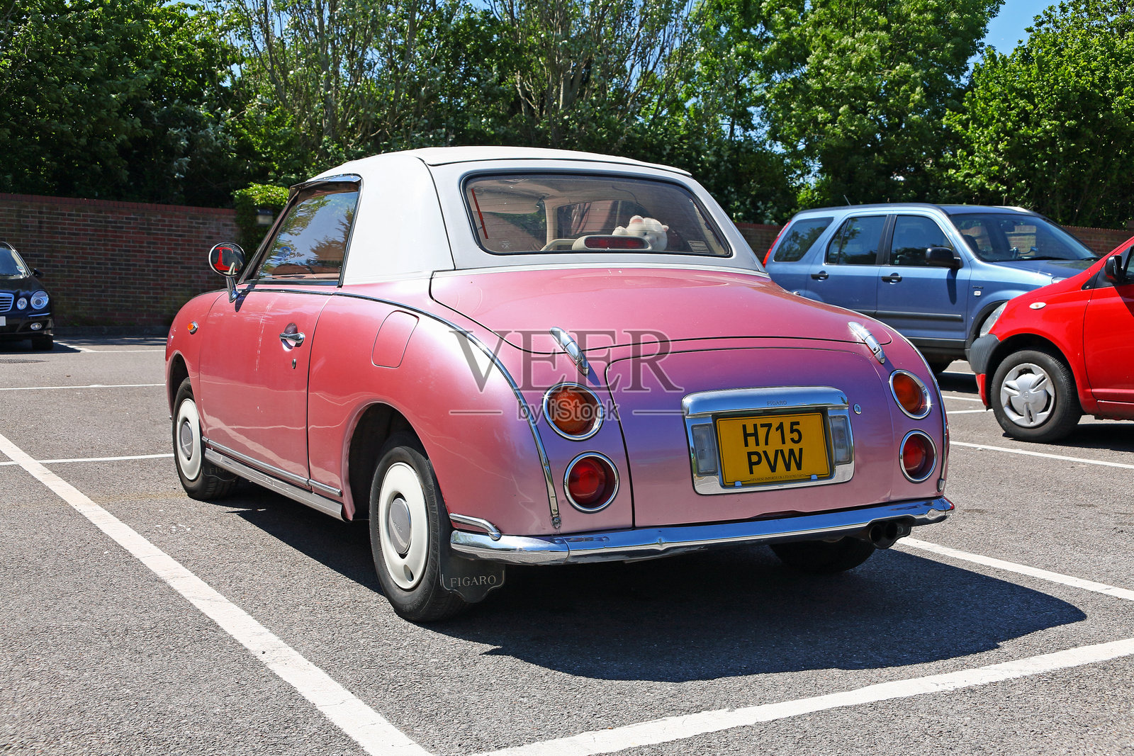 在停车场，尼桑费加罗占据了这个位置，这是一辆粉红色的复古车照片摄影图片