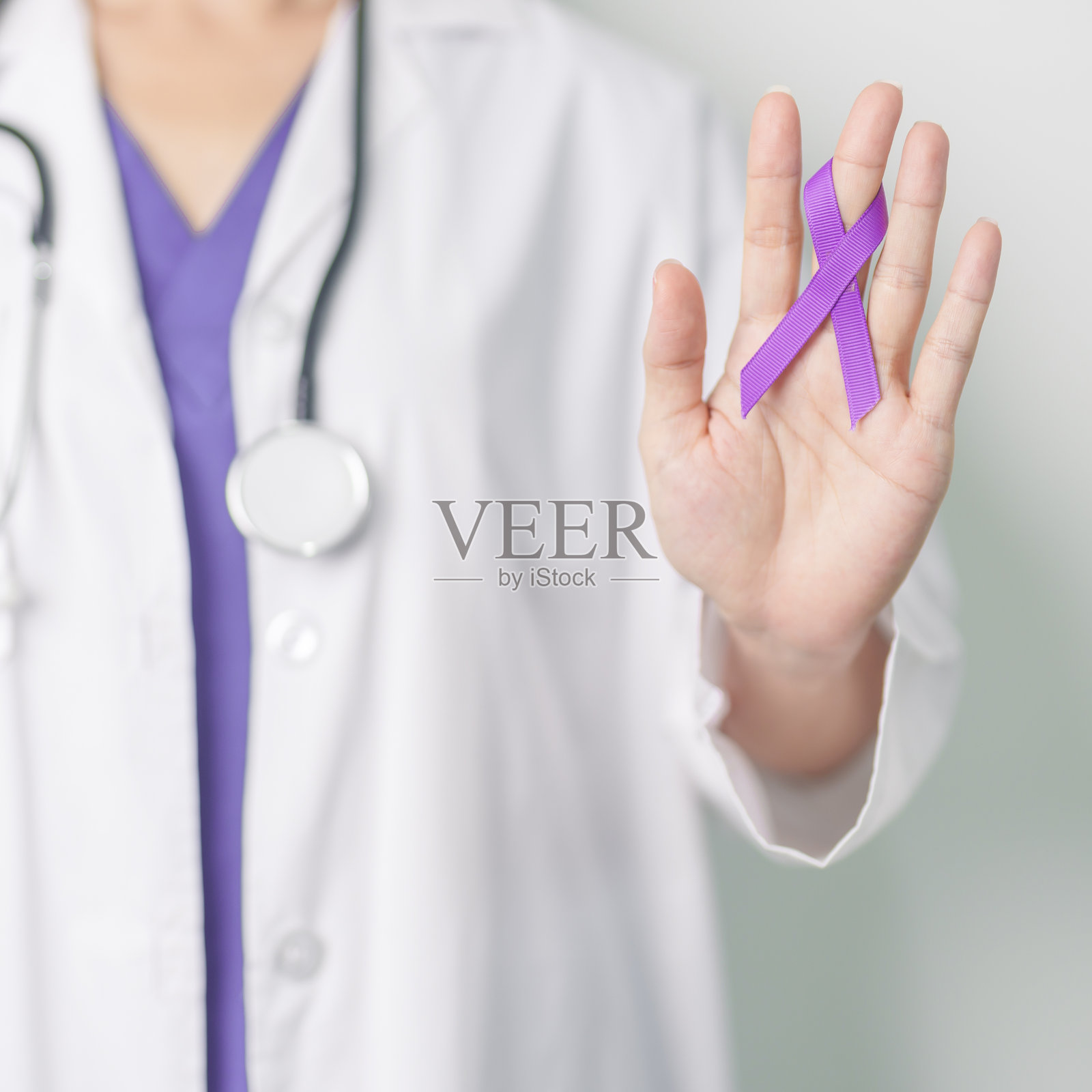 医生手持紫色丝带，用于治疗暴力、胰腺癌、食管癌、、老年痴呆症、癫痫、狼疮、结节病和纤维肌痛。宣传月和世界癌症日的概念照片摄影图片