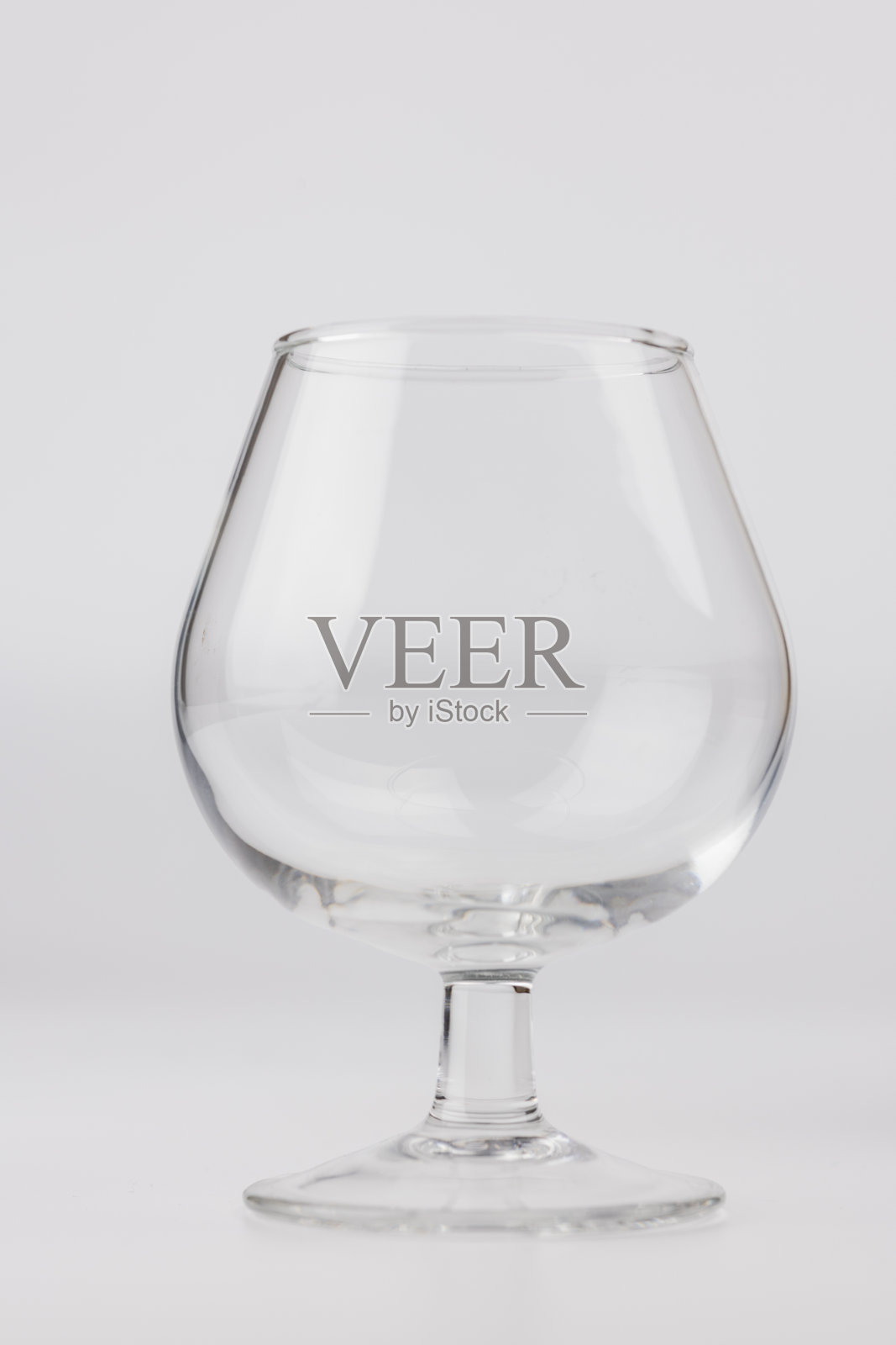 优雅的垂直照片，一个空的酒杯对一个极简主义的白色背景为中心照片摄影图片