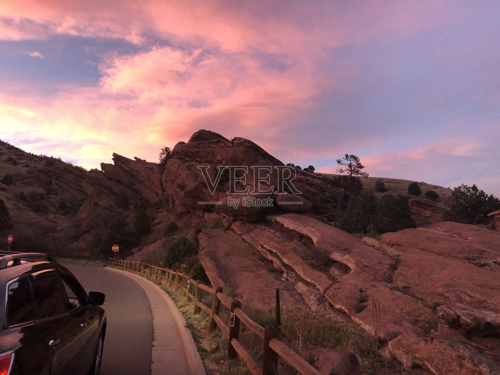 我们坐在红岩旁，落日余晖在云中嬉戏。照片摄影图片