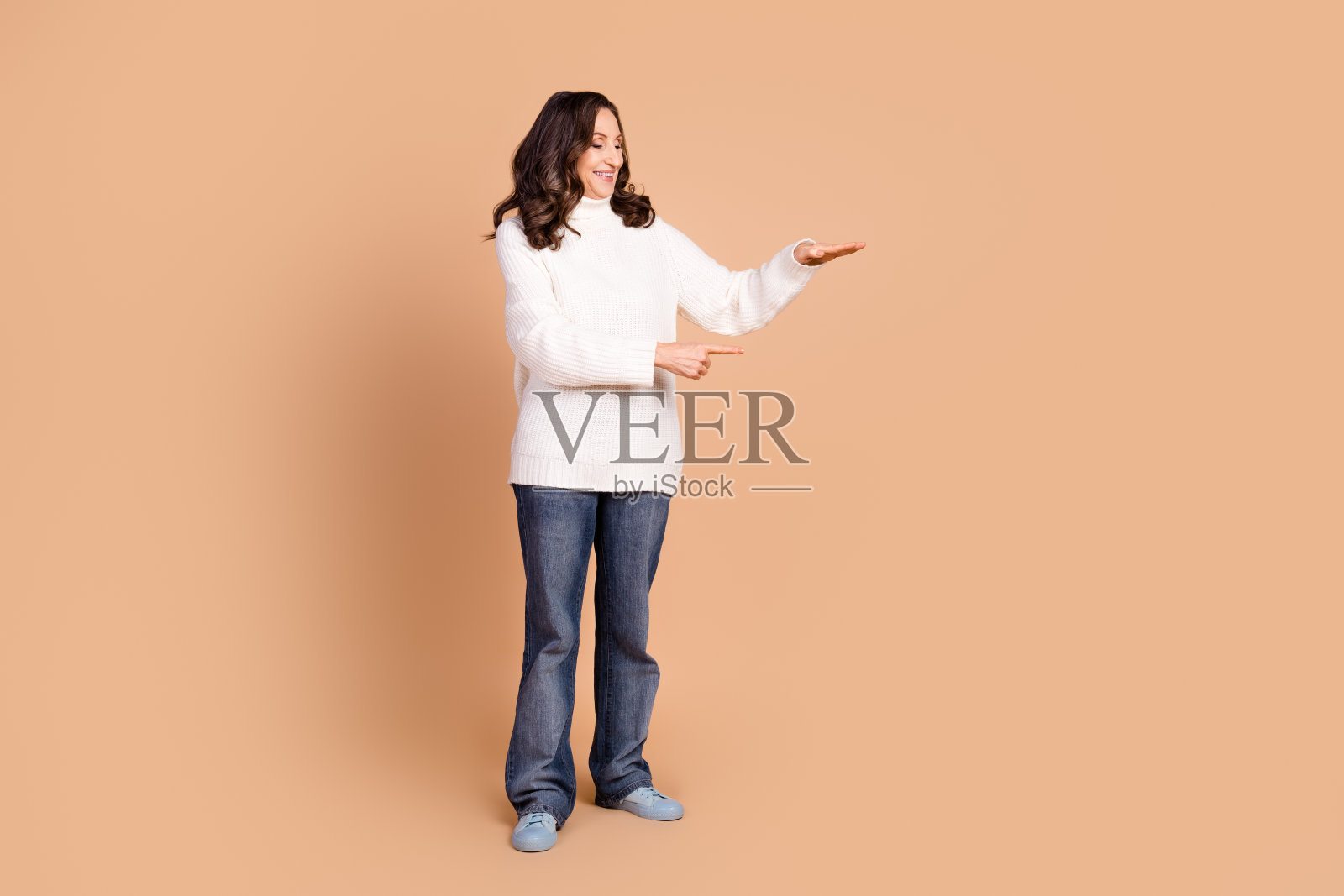 照片中迷人漂亮的美女穿着时尚的衣服，在米色背景上呈现出孤立的空白空间照片摄影图片