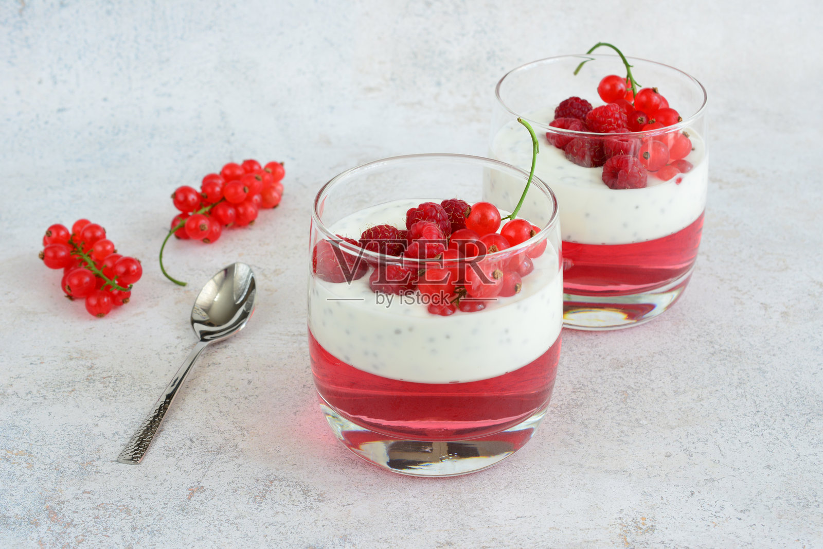 一杯有覆盆子、奇亚籽和勺子的酸奶照片摄影图片