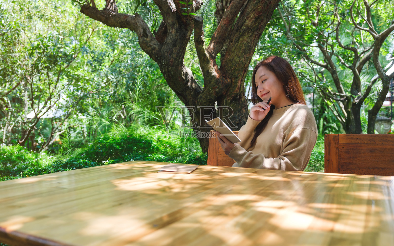 一个女人在花园里在笔记本上写字的肖像照片摄影图片