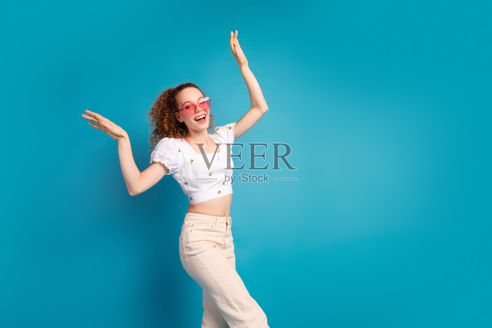 照片肖像迷人的年轻女子心形太阳镜跳舞穿着时尚的白色衣服孤立的蓝色背景照片摄影图片