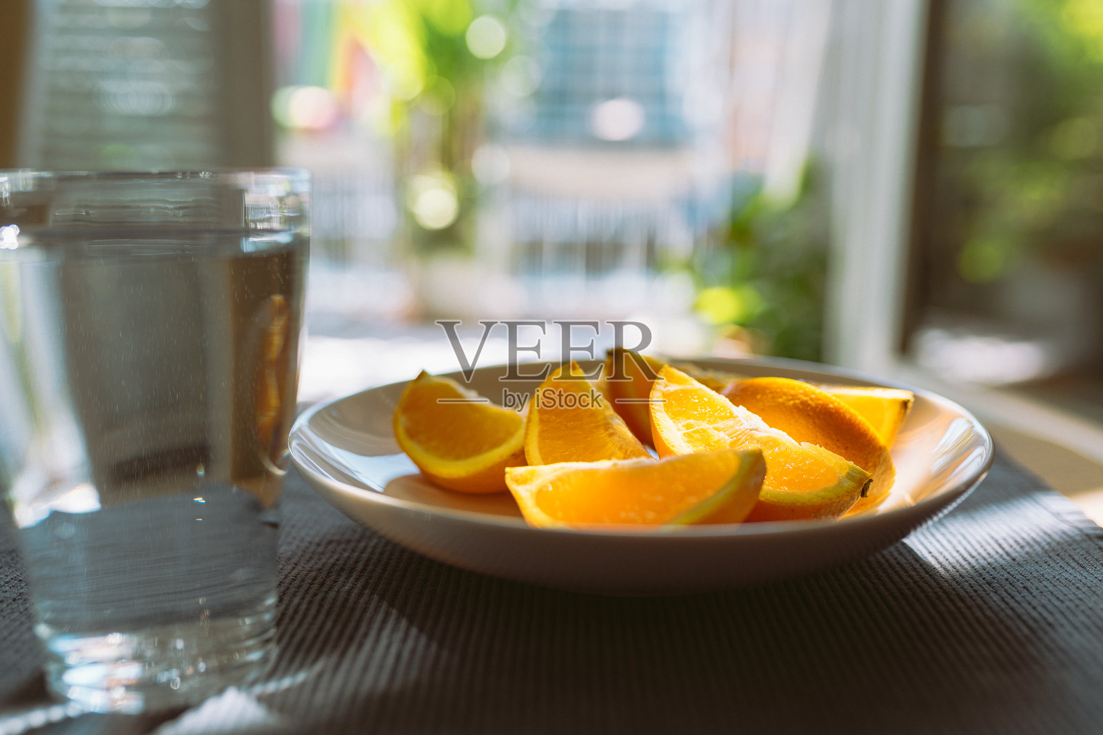 去皮的橘子和一杯水放在桌上照片摄影图片