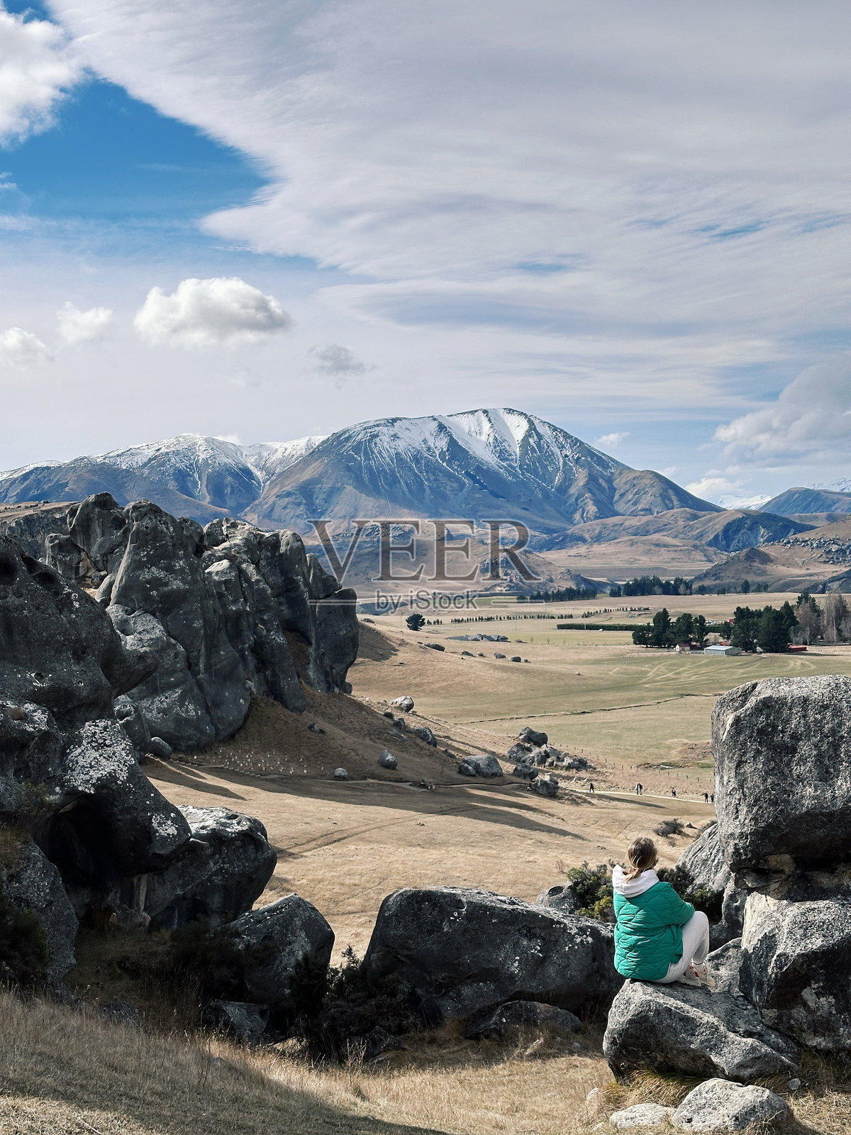 新西兰城堡山公园，一位女游客坐在一块巨大的天然石头上。旅游景点。照片摄影图片