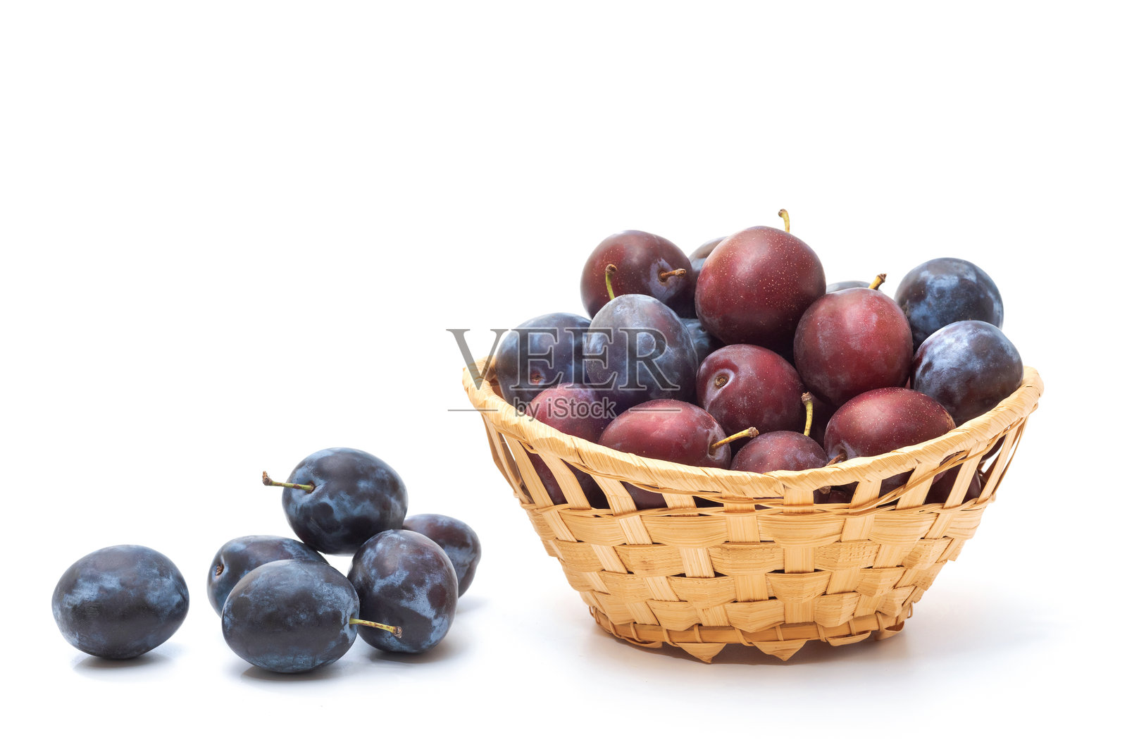 成熟的李子放在白色背景的篮子里。有机水果照片摄影图片