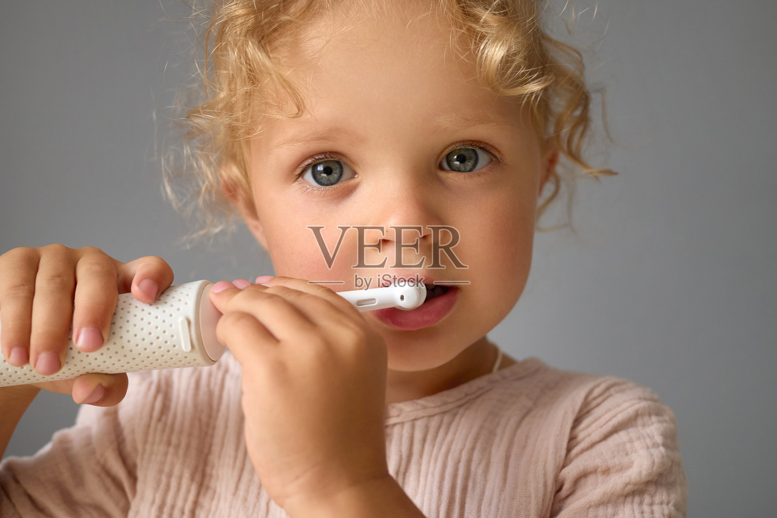 孩子的口腔健康。儿童口腔卫生。可爱的幼儿刷牙。卷发小女孩刷牙享受健康的童年习惯和口腔卫生保健照片摄影图片