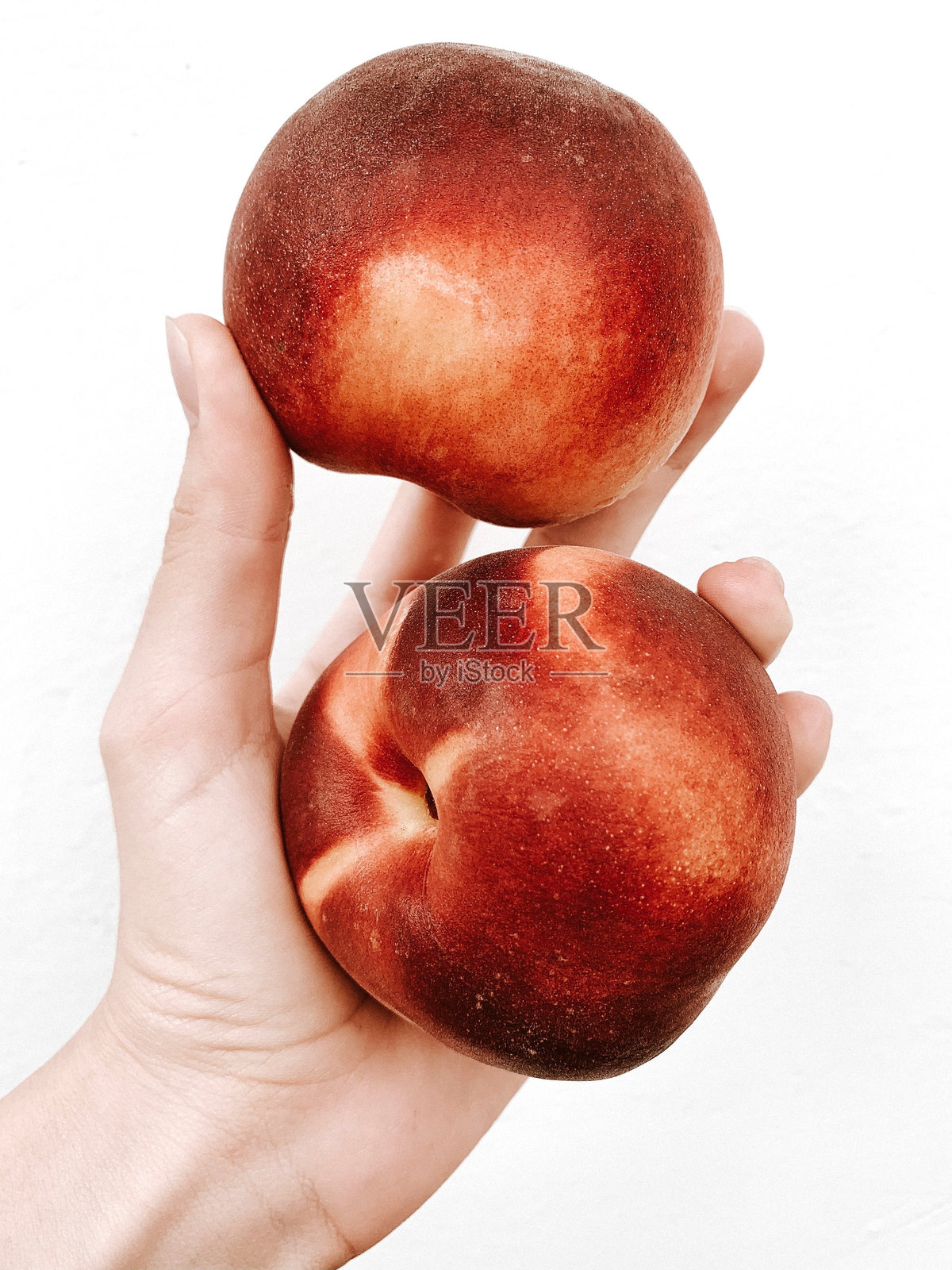 手里有两个桃子。甜的桃子。身体部位和水果。移动摄影照片摄影图片