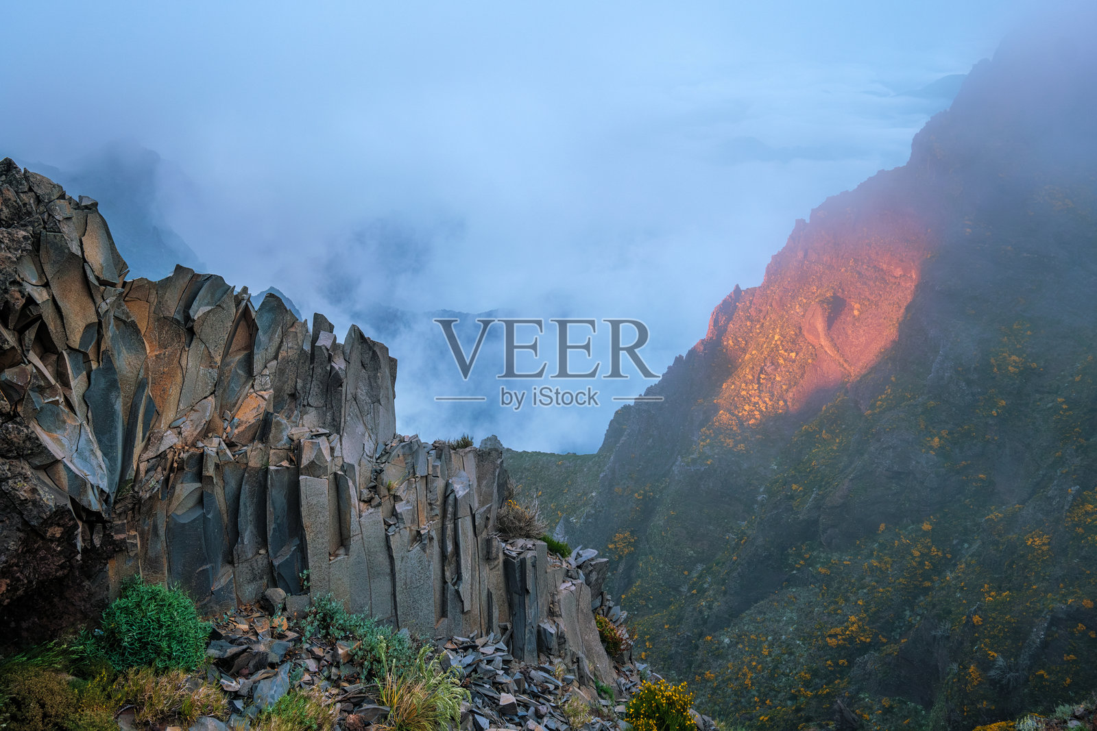 夕阳下的群山笼罩在云雾之中。葡萄牙马德拉岛照片摄影图片