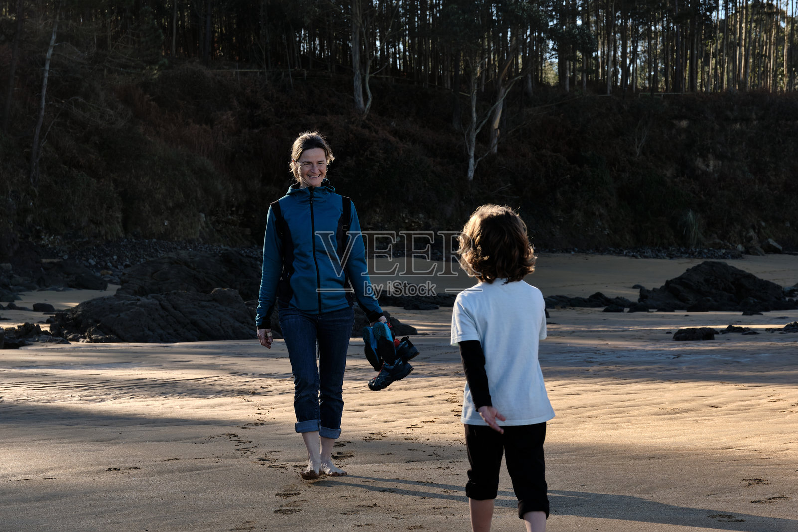 母亲和孩子赤脚走在沙滩上照片摄影图片